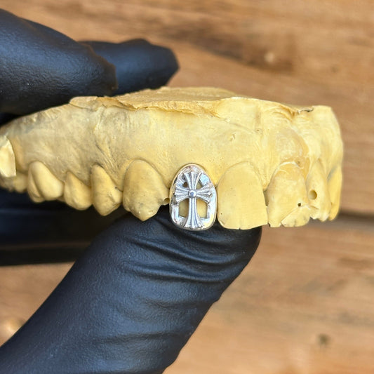 Dental model with chrome hearts cross grillz on them , silver cap holding 
